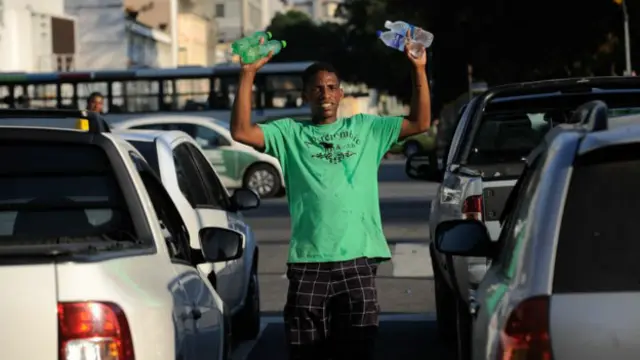 Ambulantes aproveitam para ganhar dinheiro vendendo água para refrescar o calor no trânsito