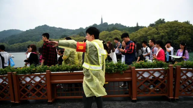工作人员在西湖指挥游客行进路线