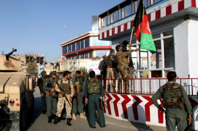 Солдаты сил безопасности Афганистана поднимают национальный флаг в Кундузе