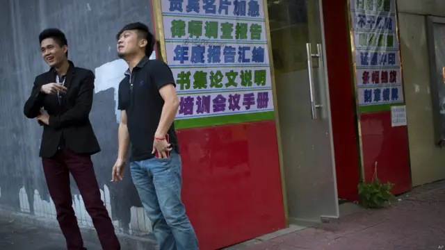 两名男性烟民在北京一栋大厦外吸烟。