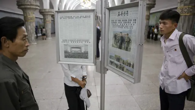 Люди читают газеты на стенде 