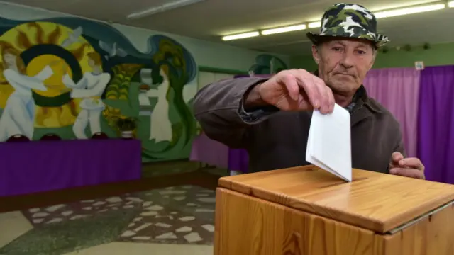 Избиратель опускает бюллетень в урну