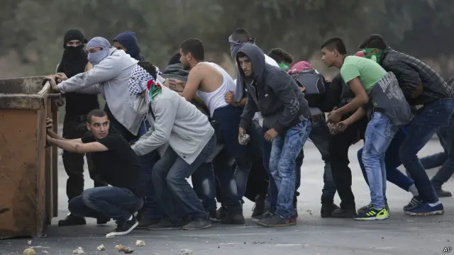 فلسطينيون يحاولون الاحتماء من رصاص الجيش الإسرائيلي في رام الله بالضفة الغربية المحتلة.