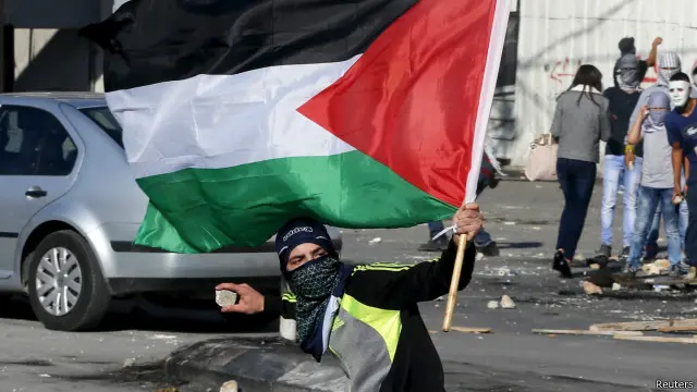 شاب فلسطيني يلقى حجرا على الشرطة الإسرائيلية عن نقطة تفتيش بين مخيم شعفاط للاجئين والقدس.