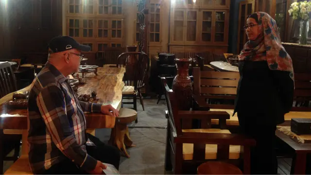 Ansah, kanan, tenaga penjualan sedang menghadapi pelanggan yang mencari meja makan dari kayu trembesi.