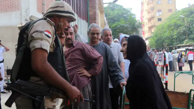 سيدة تستفسر من أحد أفراد الجيش داخل لجنة تصويت