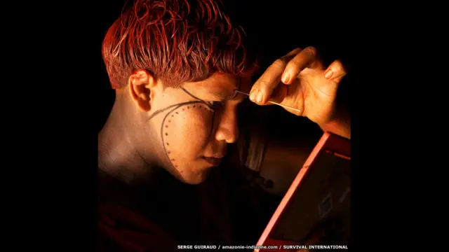 برازیل کے ایمازون علاقے میں یاوالاپتی قبیلے کا ایک فرد اپنے چہرے پر نقش و نگار بنا رہا ہے۔ یہ تصویر سرگئی گویرود نے بنائی۔