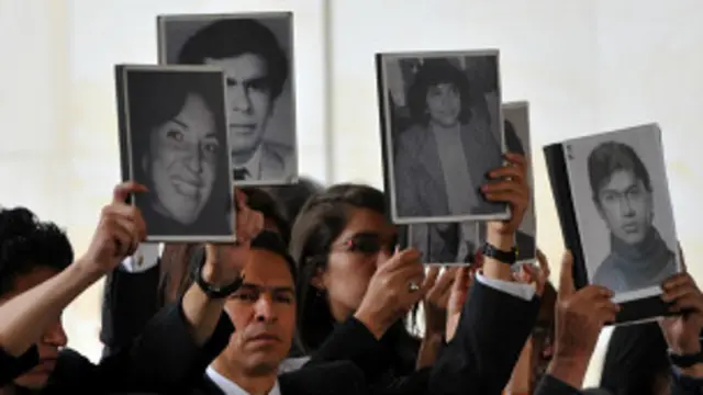Familias de las víctimas sostienen sus fotografías en una ceremonia conmemorativa en 2005.