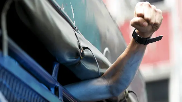 Una persona que protesta sacando su brazo por la ventana de un autobús