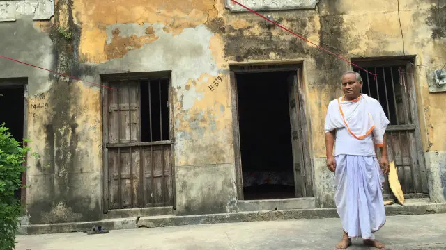 পুরোনো জীর্ণ বাড়ীর সামনে উলপুরের মন্দিরের পুরোহিত সন্তোষ ভট্টাচার্য