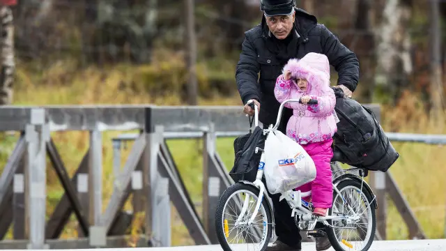 رجل يدفع الدراجة بصبية لعبور الحدود إلى النرويج