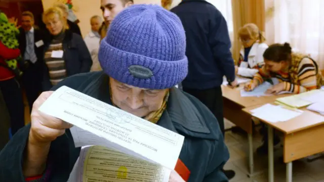 Літня жінка розглядає виборчий бюлетень