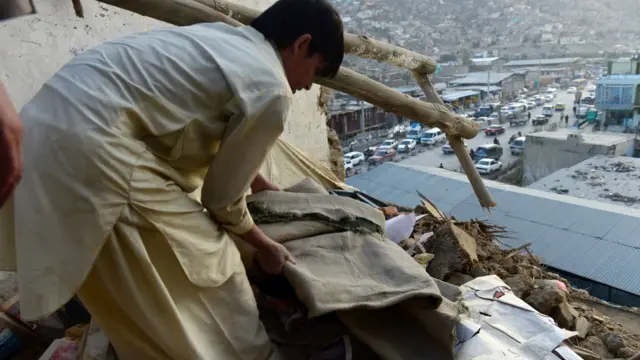 أفغاني يرفع الأنقاض عن سقف منزل