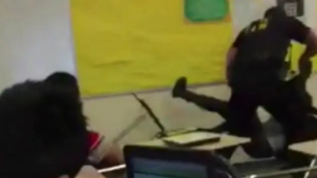 ایک افسر بچی کو گھسیٹ کر کلاس روم سے باہر لے جاتے ہوئے دیکھا جا سکتا ہے