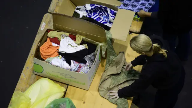 Sukarelawan melipat dan memasukkan donasi pakaian ke kotak-kotak di pusat penampungan sumbangan di hall pameran Messe di Hamburg, Jerman.