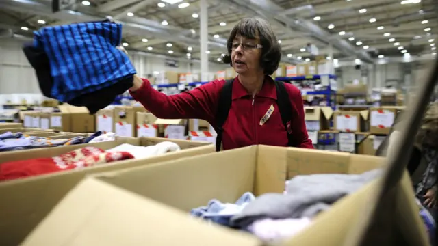 Sukarelawan melipat dan memasukkan donasi pakaian ke kotak-kotak di pusat penampungan sumbangan di hall pameran Messe di Hamburg, Jerman.