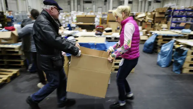 Erika, sukarelawan berusia 74 tahun, melipat dan memisahkan pakaian anak-anak di pusat penampungan donasi buat migran di hall pameran Messe, Hamburg, Jerman. 