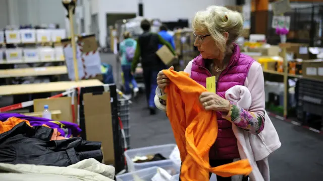 Erika, sukarelawan berusia 74 tahun, melipat dan memisahkan pakaian anak-anak di pusat penampungan donasi buat migran di hall pameran Messe, Hamburg, Jerman. 