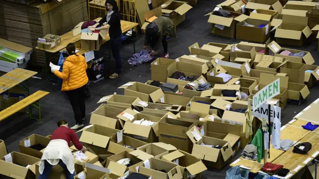 Sukarelawan melipat dan memasukkan donasi pakaian ke kotak-kotak di pusat penampungan sumbangan di hall pameran Messe di Hamburg, Jerman.