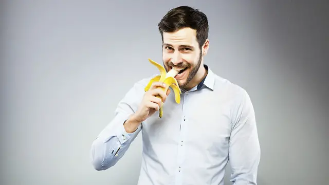 Молодой человек ест банан