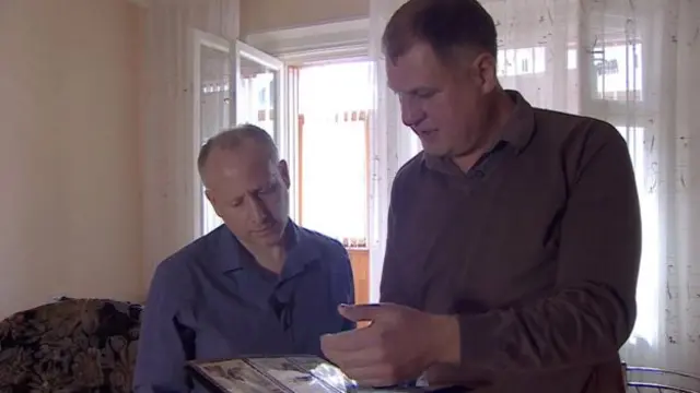 巴拉巴诺夫（右）向记者展示他阿富汗战争期间的老照片