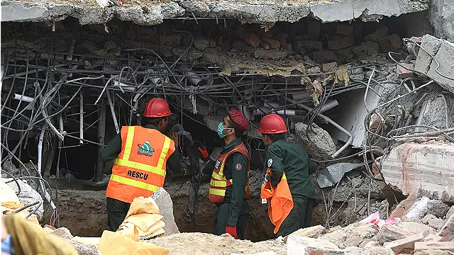 بھاری مشینری کی مدد سے عمارت کی اوپری منزل کا ملبا ہٹایا جا رہا ہے