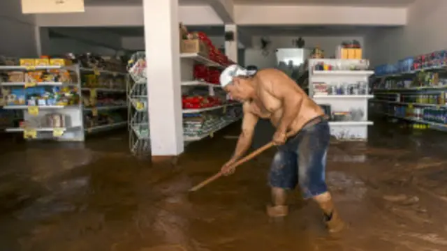 Un hombre remueve el lodo de la inundación.