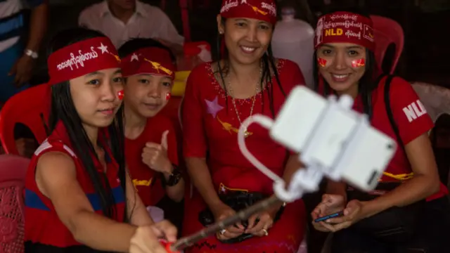 Pendukung kelompok oposisi Myanmar berfoto di depan markas NLD di tengah hujan deras.