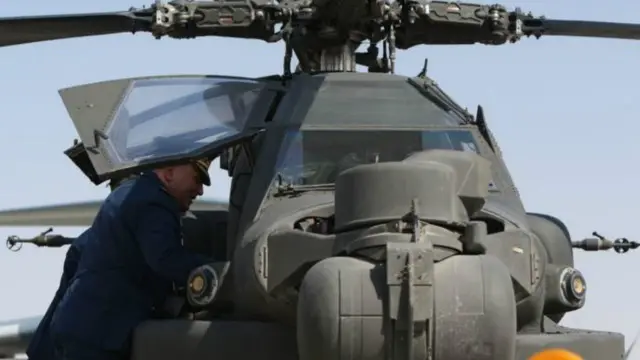 أحد زوار المعرض يتفقد نموذجا من طائرة آباتشي الهجومية الأمريكية. تأمل شركة بوينغ تسويق هذه الطائرة بالإضافة إلى الطراز الأصغر AH-6i، والتي اشترتها منها بالفعل السعودية والأردن.