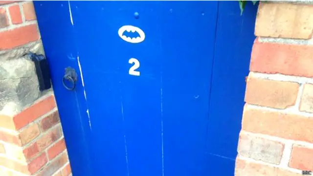 Puerta de una casa en Gotham con un símbolo de Batman