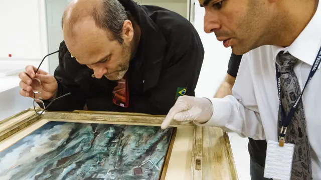 Peritos Ivan Ferreira (à esq.) e Aldemar Maia Neto (dir.) inspecionam obra apreendida na Lava Jato e de autoria atribuída a Alberto da Veiga Guignard (1896-1962)