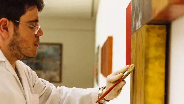 Técnico do museu Oscar Niemeyer faz manutenção de obra de Antônio Dias. "Sem título, 2011". Óleo sobre tela, 90 x 136 cm.