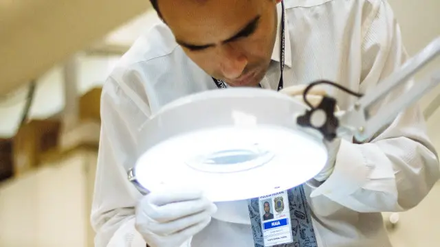 Perito observa coleta de amostra de tinta de uma das obras apreendidas; objetivo é verificar autenticidade e valor de mercado