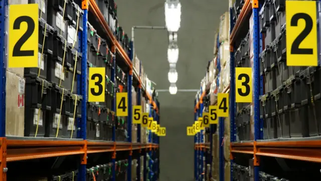 Las semillas están almacenadas en cajas de plástico en largas hileras de estantes. 