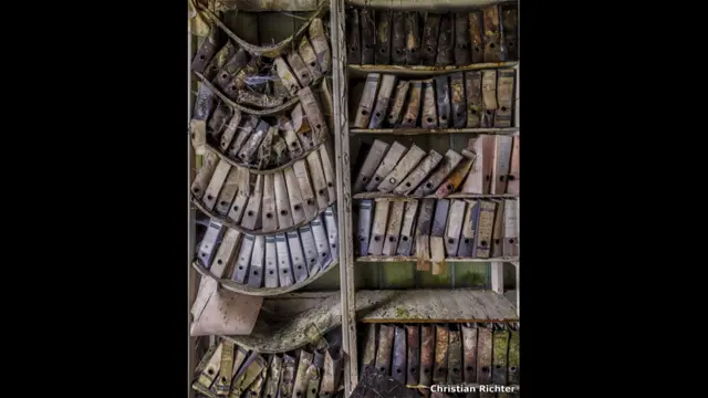 जर्जर हो रही शेल्फ पर रखी फाइलें. क्रिश्चियन रिचर