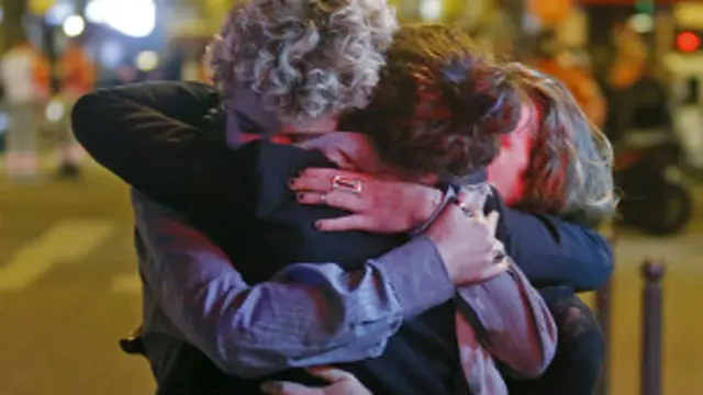 Unas personas se abrazan cerca de la sala de conciertos Bataclan.