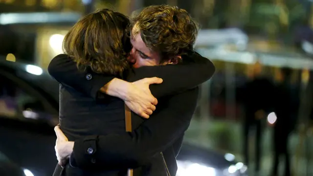 बैटाकलां कन्सर्ट हॉल के बाहर गले मिलते हमले में बचे लोग.