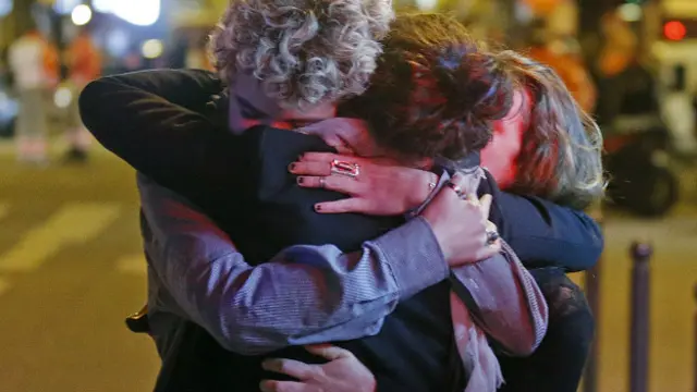 Люди обнимают друг друга рядом с театром