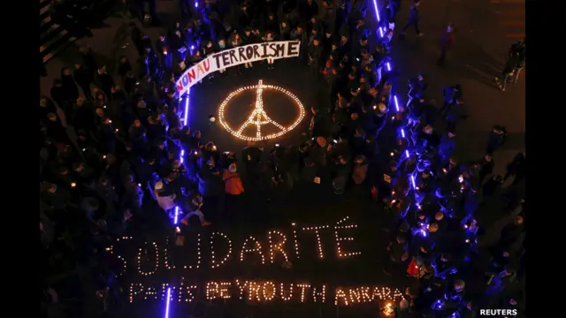 Người tưởng niệm tụ tập quanh những cây nến được xếp thành chữ Đoàn Kết Paris Beyrouth Ankara trong một buổi lễ dành cho nạn nhân được tổ chức tại Lausanne, Thụy Sĩ. Họ cũng cầm biểu ngữ với hàng chữ "Nói không với nạn khủng bố".