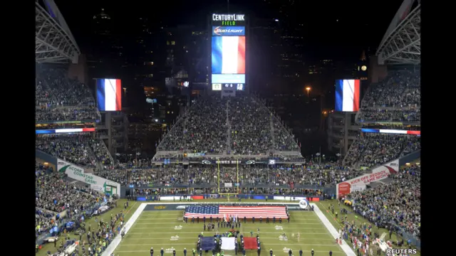 Cờ Pháp và Mỹ được diễu hành trên sân sau phút mặc niệm trước trận bóng giữa đội Arizona Cardinals và đội Seattle Seahawks tại sân CenturyLink Field ở Seattle, Hoa Kỳ.