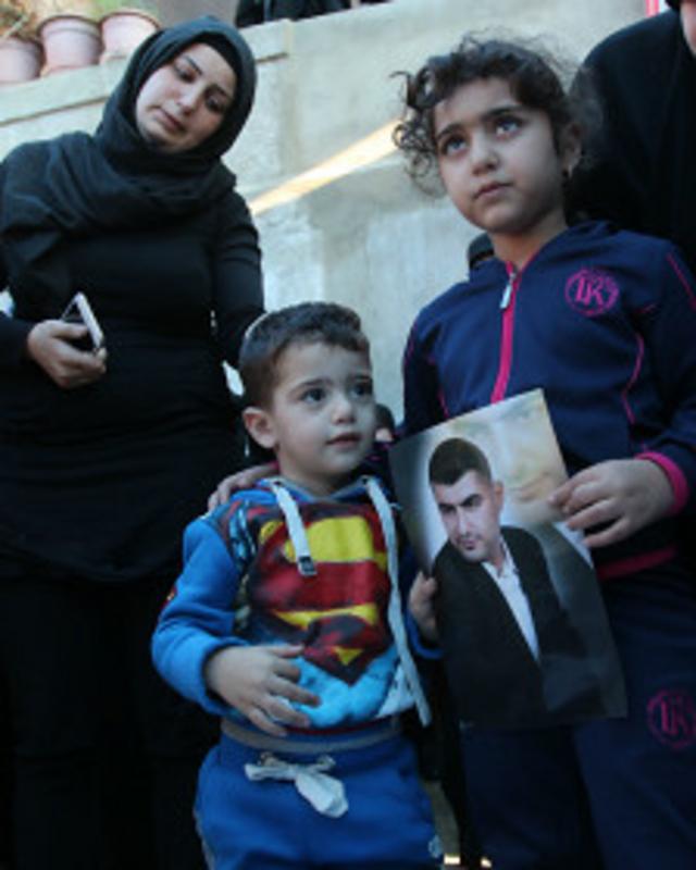Ali (à esq.) e Malak (dir.) levam a fotografia de Adel Termos durante funeral do pai
