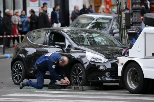 Полицейский собирается буксировать машину, оставленную подозреваемыми в пятничных нападениях