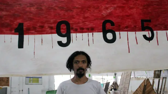 Setu Legi dari Lembaga Budaya Kerakyatan Taring Padi berdiri di depan karyanya yang berjudul 'Masa Depan Tenggelam Dalam Masa Silam'.