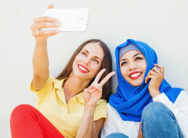Европейская и мусульманская девушка делают сэлфи