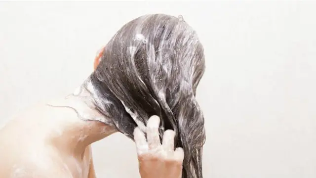 Una persona enjabonándose el cabello