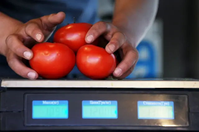Продавец взвешивает помидоры на одном из рынков