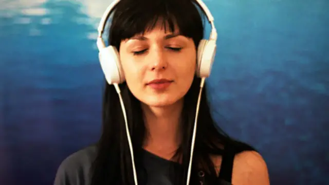 一名女子戴着耳机，聆听音乐。（图片来源：Getty Images）