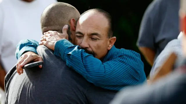 Dos personas se abrazan afuera del edificio donde se produjo el tiroteo.