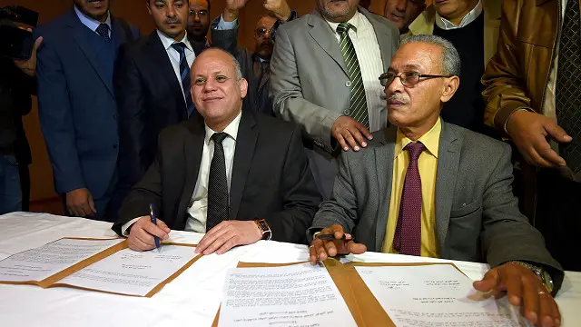 إبراهيم فتحي عميش (يمين) من البرلمان المعترف به دوليا، و عوض محمد عبد الصادق من المجلس الوطني العام خلال توقيع الاتفاق.