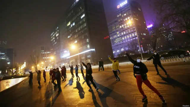 بیجنگ میں فضائی آلودگی کے باوجود کچھ لوگ کھلی جگہ پر رات کے وقت جسمانی ورزش کر رہے ہیں۔ 